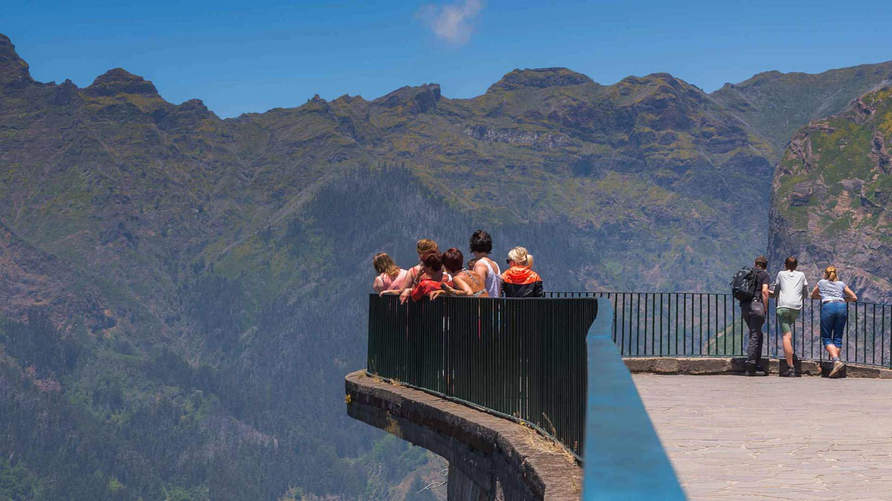 a group of people sitting on a bench in front of a mountain